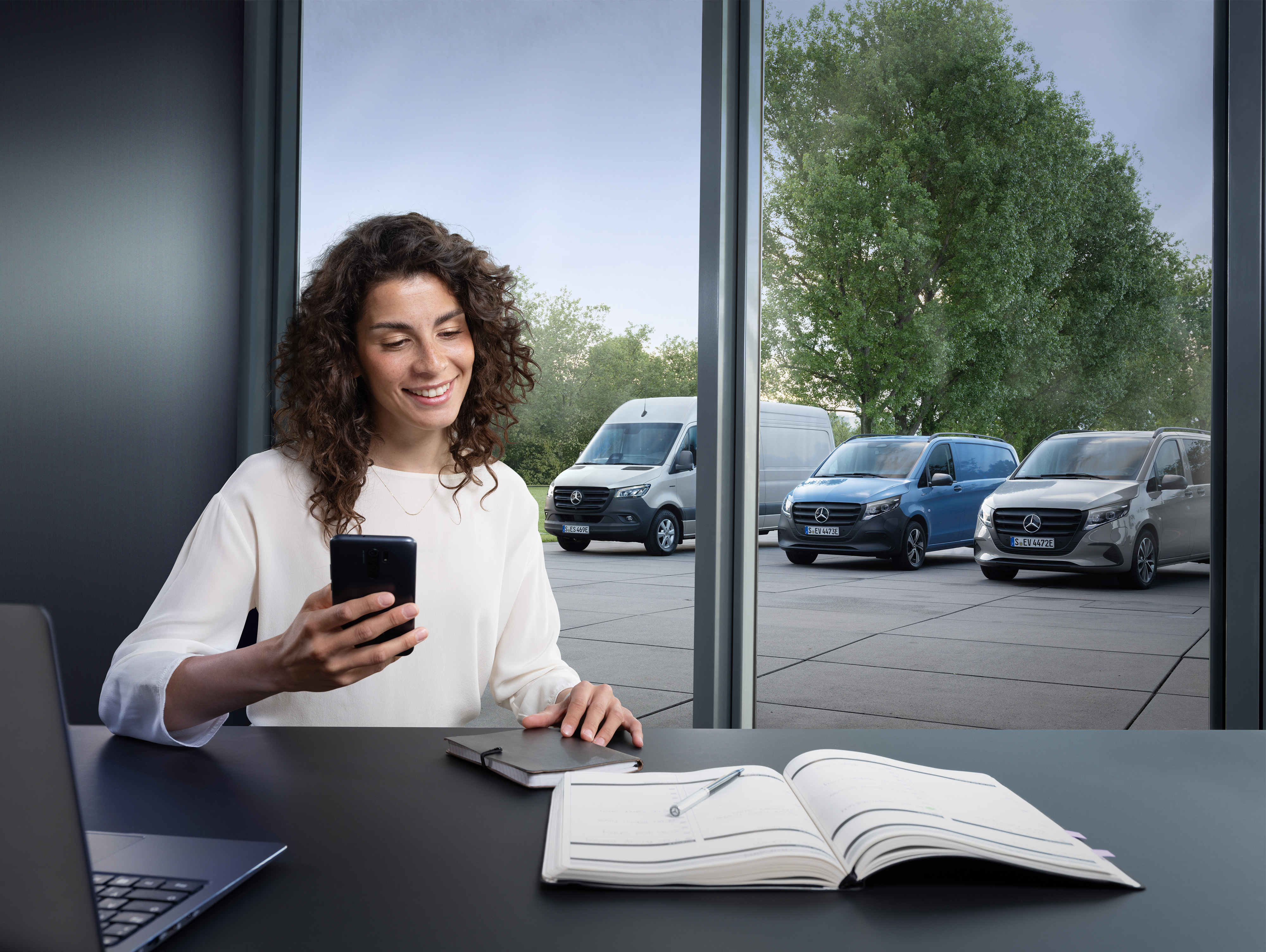 Mercedes-Benz | Van ServiceCare | Appointment booking Una donna con uno smartphone e un planning sul tavolo