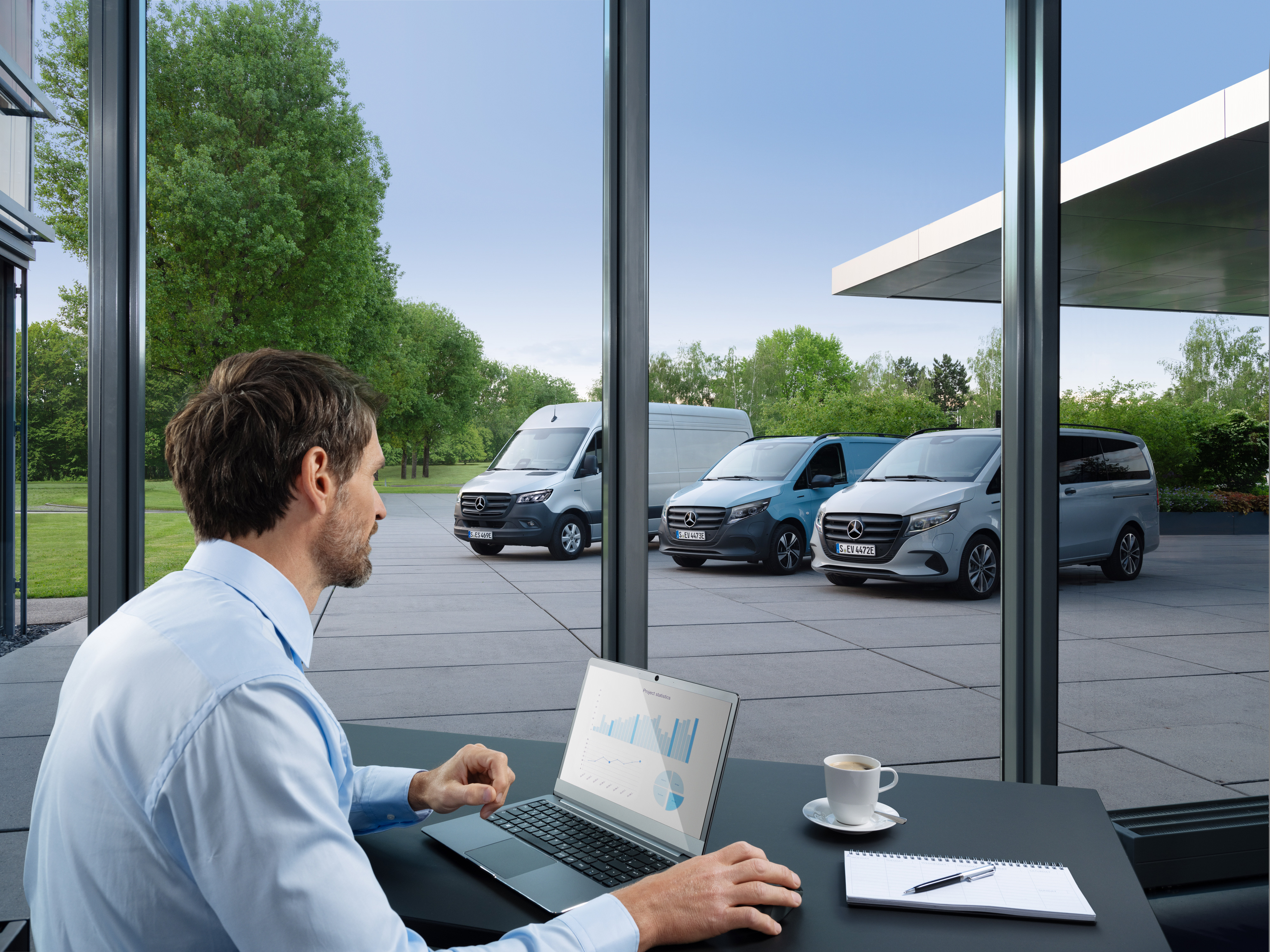 Mercedes-Benz | Tecnologia per veicoli commerciali | Van Uptime Monitor Un uomo controlla diversi veicoli commerciali Mercedes-Benz parcheggiati con un computer portatile