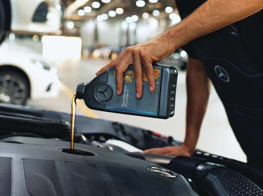 Primo piano del vano motore nel momento in cui viene rabboccato l'olio motore originale Mercedes-Benz.