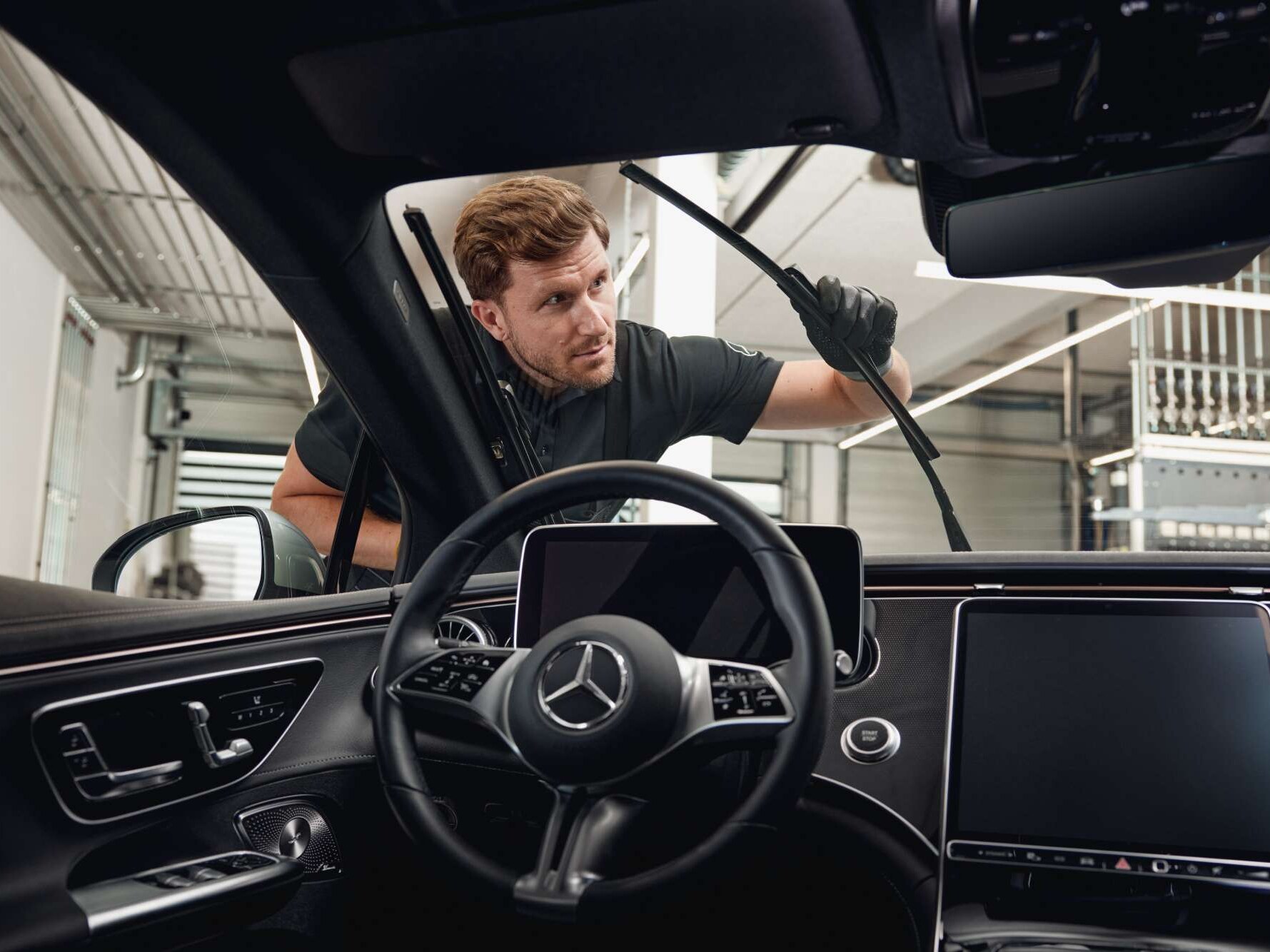 Vista interna di un veicolo Mercedes-Benz mentre un tecnico sostituisce le spazzole del tergicristallo.