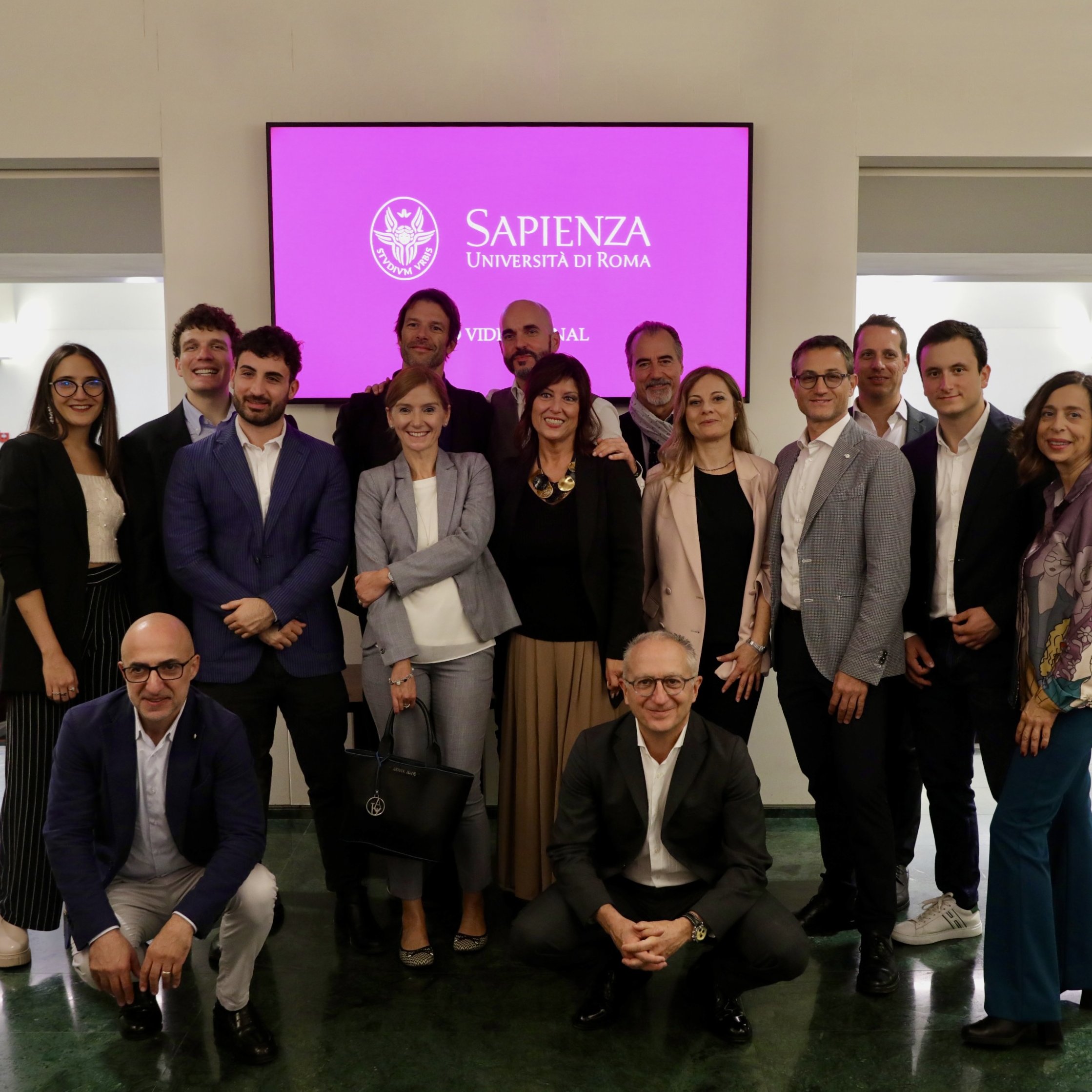Cultura aziendale | Mercedes-Benz Foto di gruppo con sullo sfondo il logo dell'Università La Sapienza.