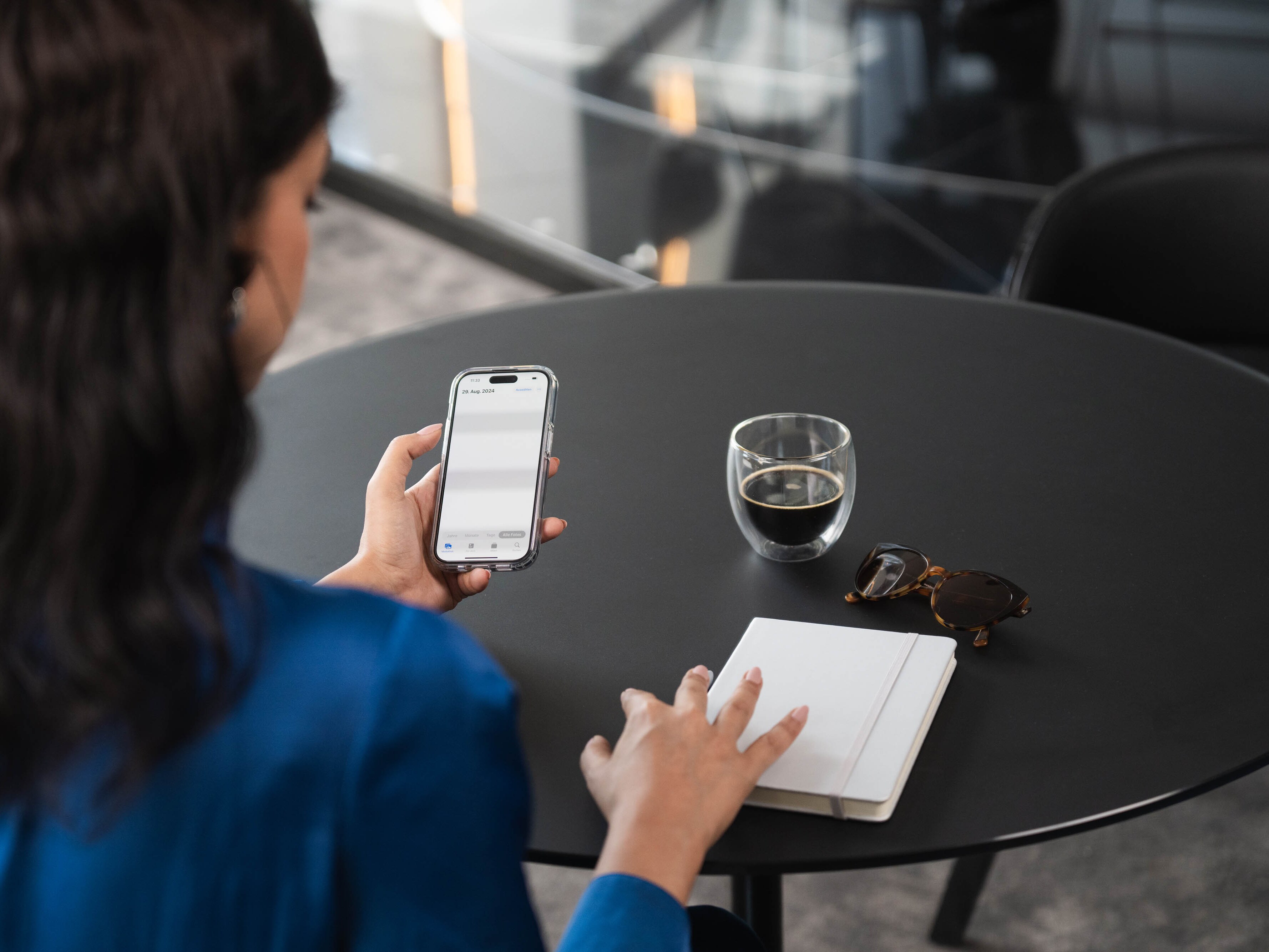 Una donna con uno smartphone tra le mani e un taccuino sul tvolo