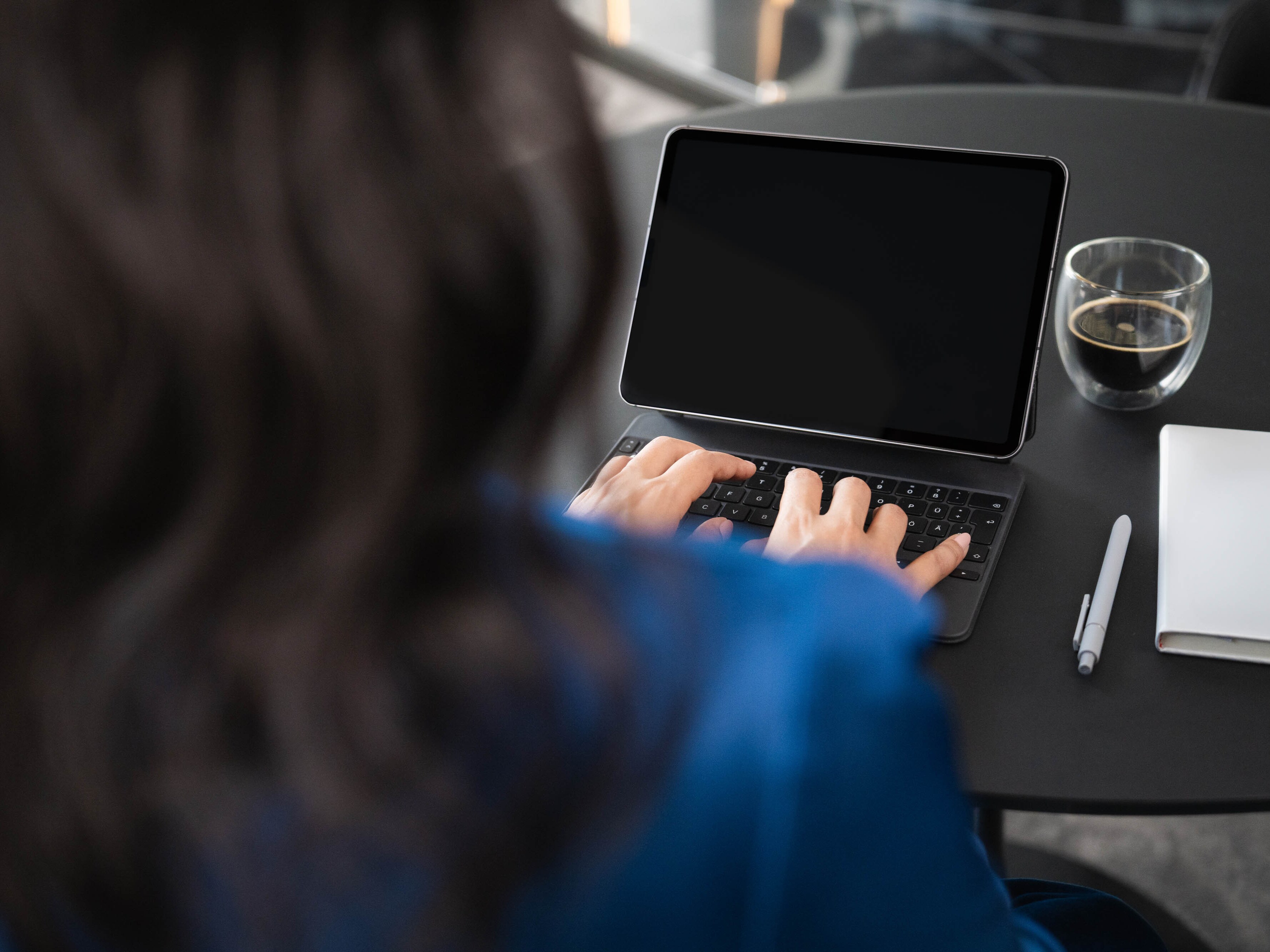 Una donna di fronte a un tablet digita sulla tastiera