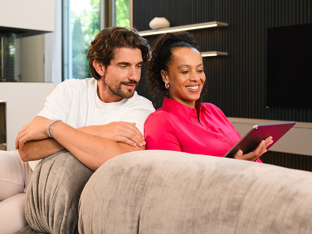 Due persone su un divano che guardano un dispositivo mobile.