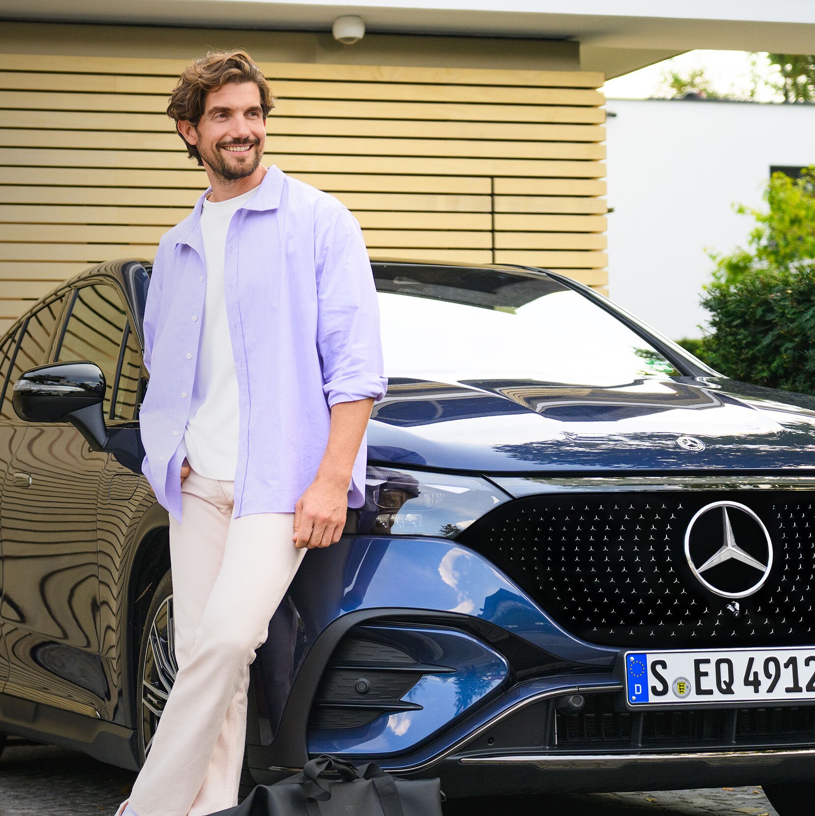 Una persona appoggiata a un veicolo Mercedes-Benz davanti alla propria casa.
