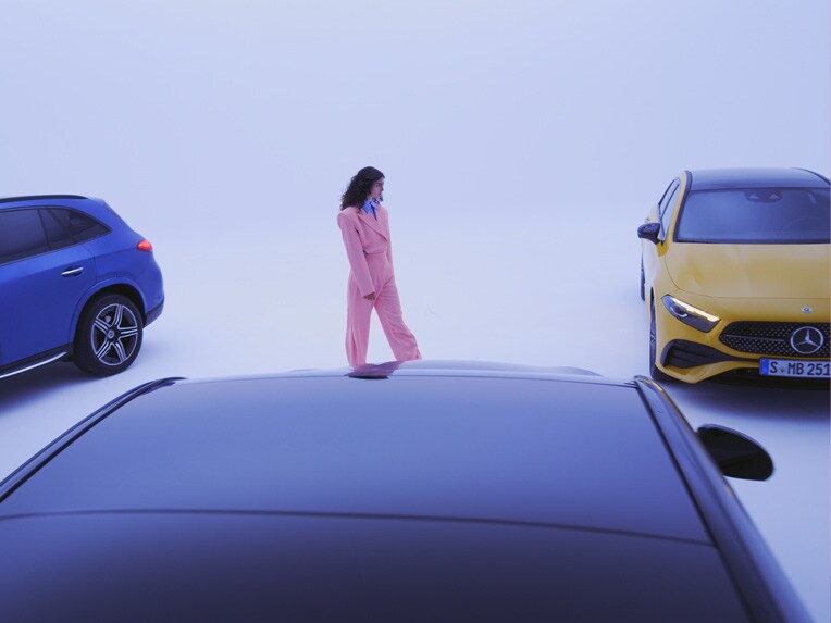 Una donna vestita di rosa tra tre modelli Mercedes-Benz