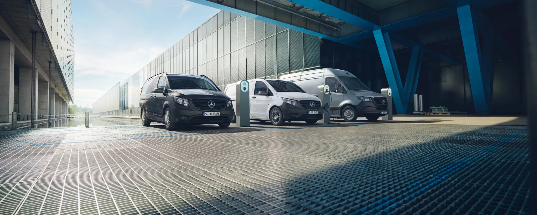 Modelli Mercedes-Ben Vans Tre modelli di Vans Mercedes-Benz con sullo sfondo una fabbrica