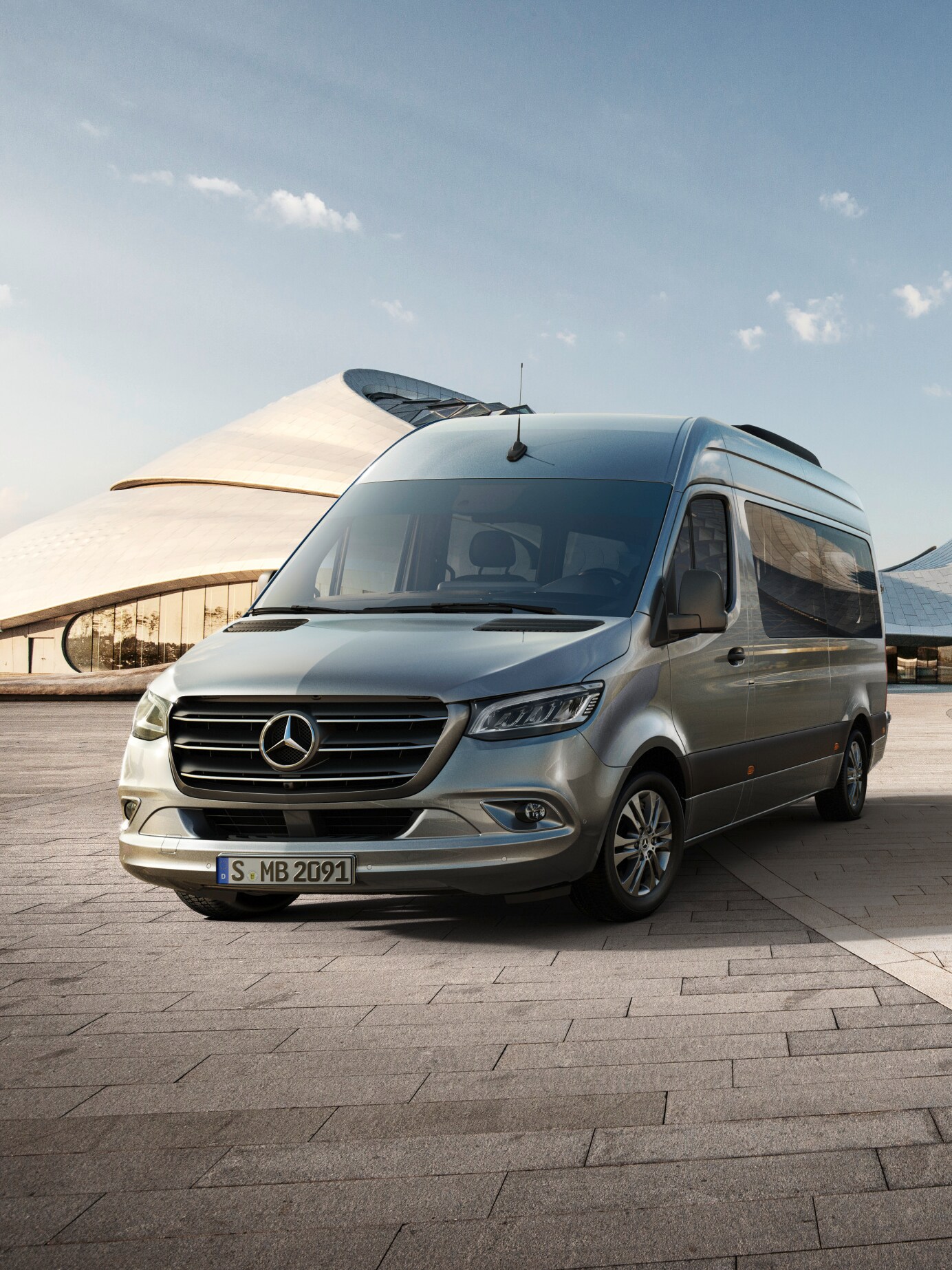 Un uomo è inginocchiato a lato della sua Mercedes-Benz per controllarla