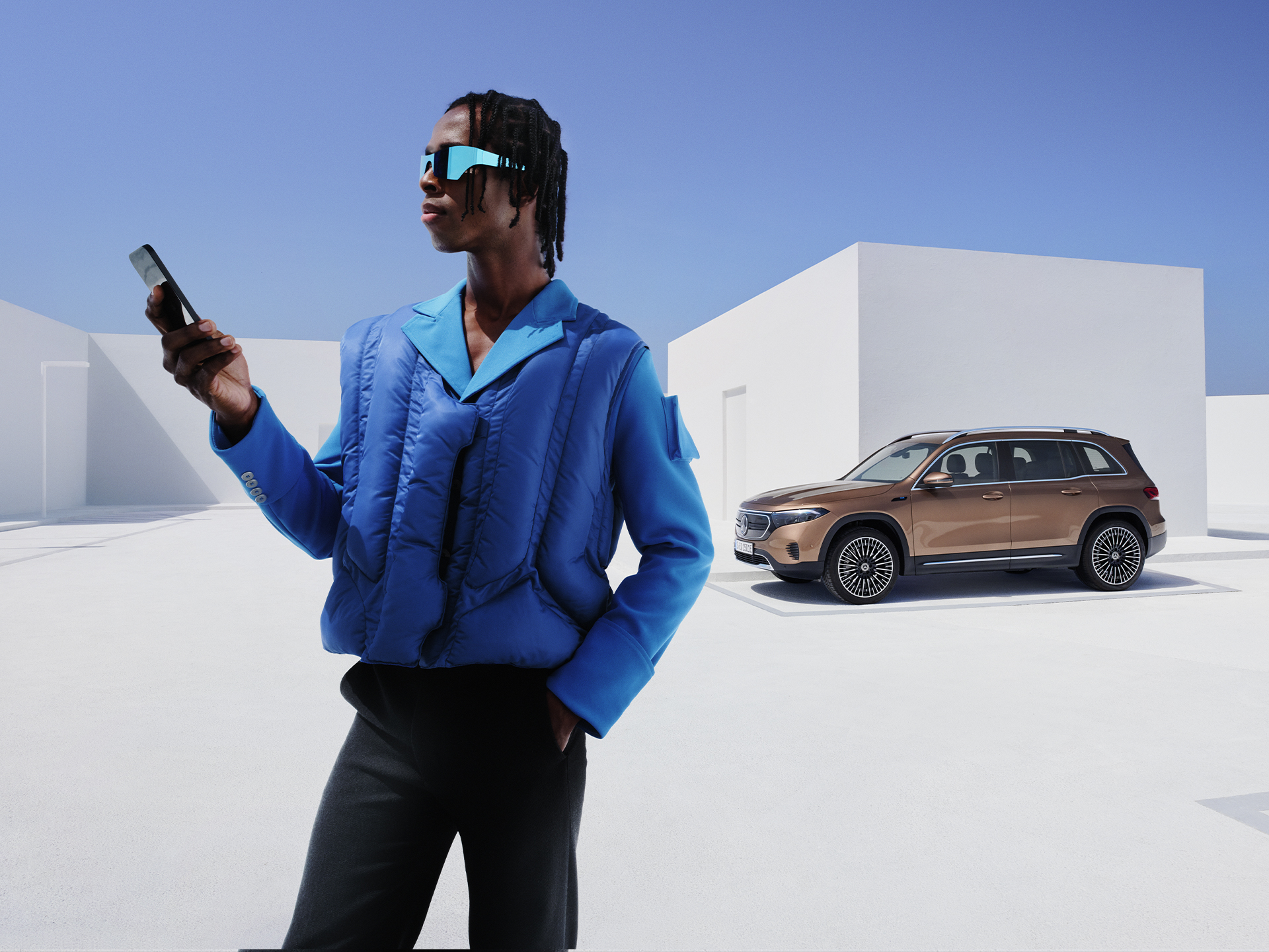 Mercedes-Benz App | Applicazioni | Mercedes-Benz Una persona con uno smartphone in mano e una auto sullo sfondo